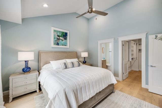 bedroom with lofted ceiling, visible vents, a spacious closet, light wood-style floors, and connected bathroom