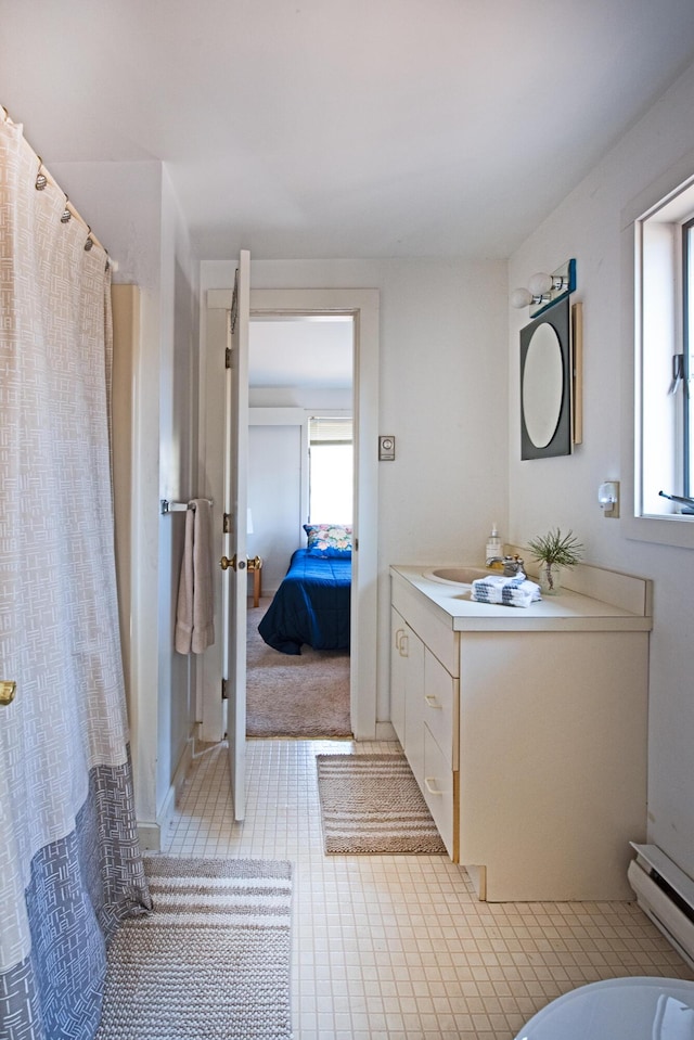 bathroom featuring vanity, a baseboard radiator, connected bathroom, and a wealth of natural light