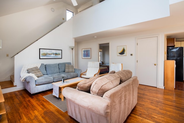 living room featuring stairs, dark wood-type flooring, and a towering ceiling