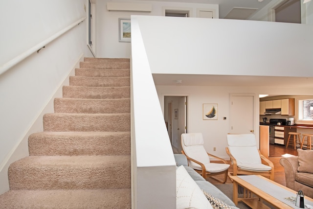 staircase with wood finished floors and a wall mounted air conditioner