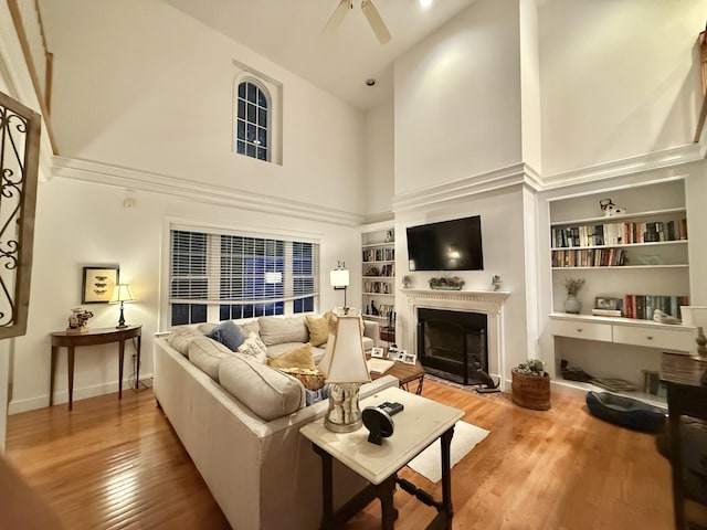 15 Hampton Ct, Mashpee, MA 02649 - living room featuring high vaulted ceiling, built in shelves, wood finished floors, a fireplace with flush hearth, and ceiling fan