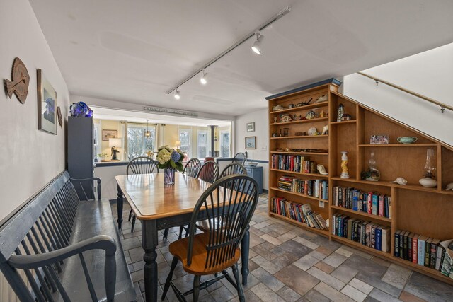 dining space featuring track lighting and stone finish flooring