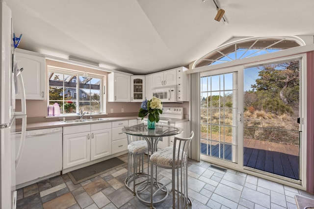 kitchen with white cabinets, a sink, visible vents, vaulted ceiling, and white appliances