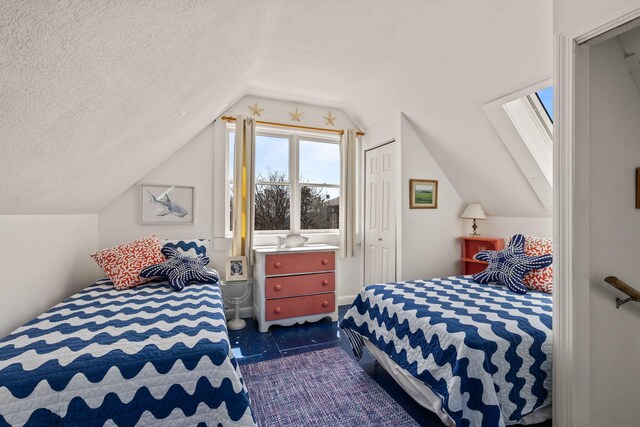 bedroom with lofted ceiling with skylight, a closet, and a textured ceiling