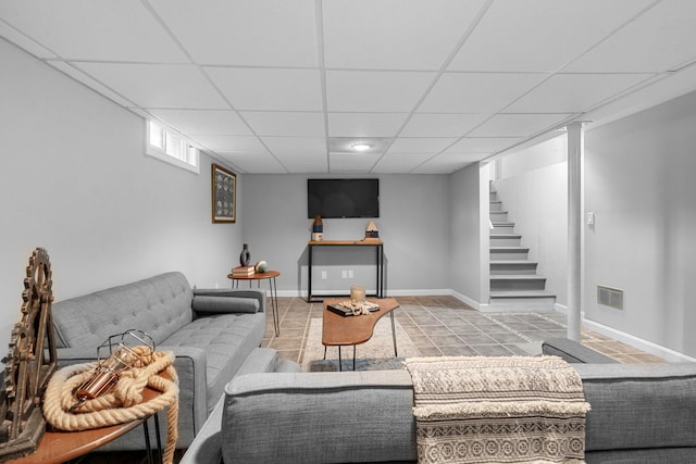 living area with a paneled ceiling, visible vents, baseboards, stairs, and tile patterned floors