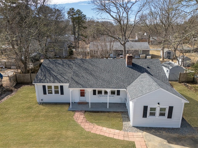 view of front facade featuring a shingled roof, a chimney, fence, and a front lawn