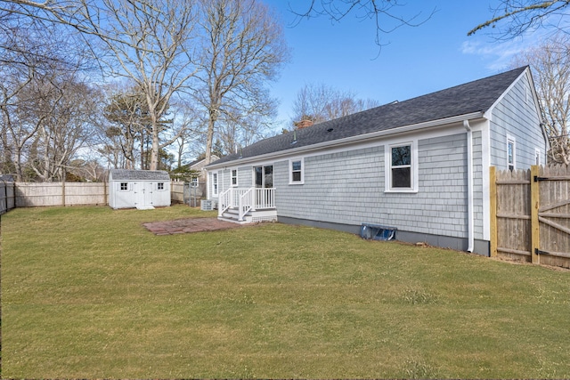 rear view of house with a fenced backyard, a chimney, an outbuilding, a yard, and a shed