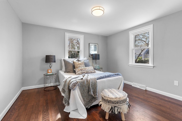 bedroom featuring multiple windows, baseboards, and wood finished floors