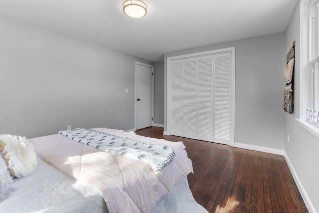 bedroom with a closet, hardwood / wood-style flooring, and baseboards