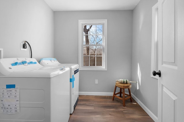 washroom featuring laundry area, dark wood-type flooring, washing machine and clothes dryer, and baseboards