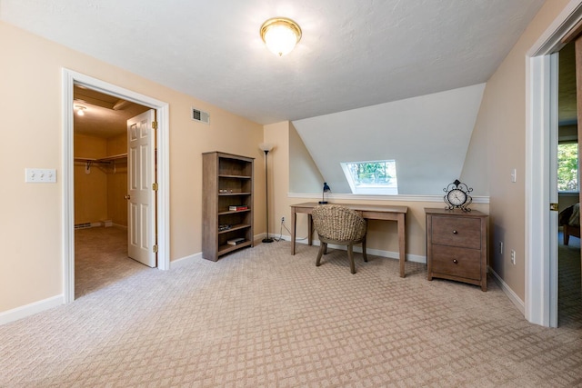 office space with vaulted ceiling with skylight and light colored carpet