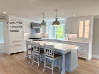 47 Daleys Ter, Orleans, MA 02653 - kitchen featuring wall chimney range hood, light countertops, backsplash, recessed lighting, and a kitchen island
