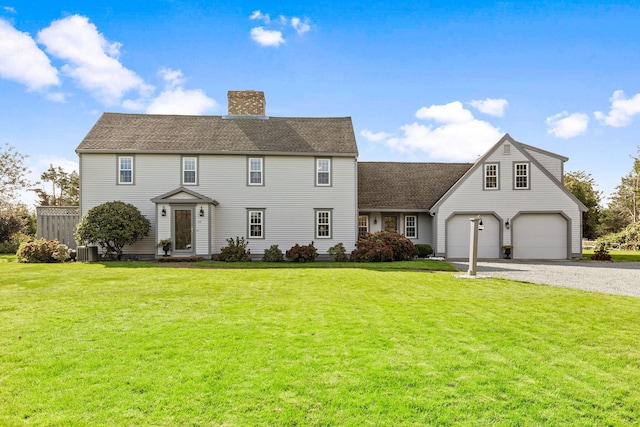 colonial home featuring a front yard, roof with shingles, cooling unit, a chimney, and driveway