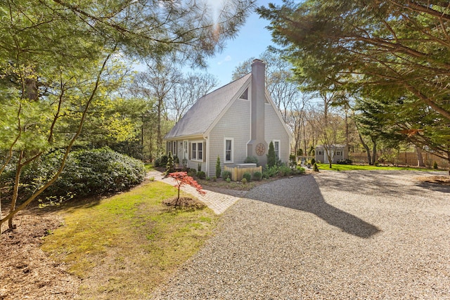11 White Oak Trl, Centerville, MA 02632 - view of side of home featuring a chimney, gravel driveway, a shingled roof, and an outdoor structure