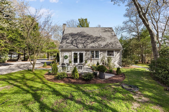 11 White Oak Trl, Centerville, MA 02632 - view of front of house with board and batten siding, a front lawn, a chimney, french doors, and roof with shingles