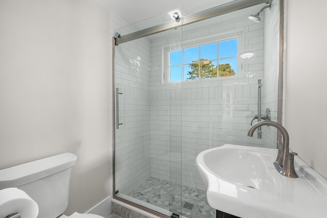 bathroom featuring sink, a shower with door, and toilet