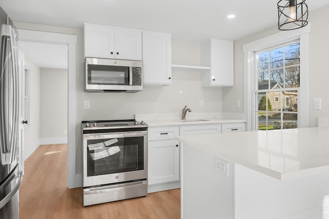 kitchen featuring decorative light fixtures, white cabinets, a wealth of natural light, and stainless steel appliances