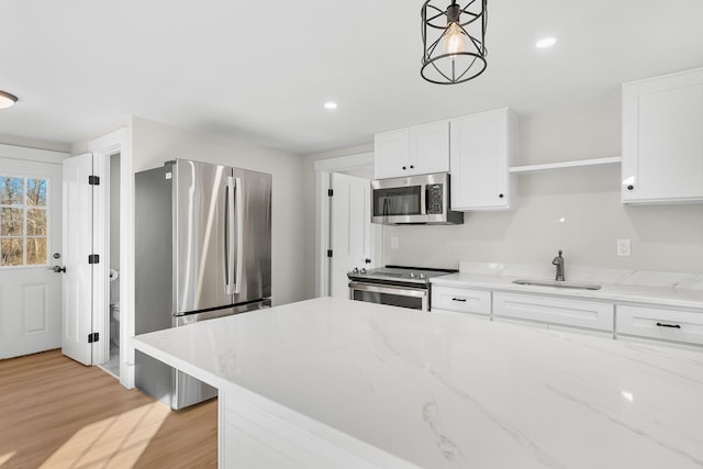 kitchen featuring light hardwood / wood-style flooring, decorative light fixtures, sink, white cabinets, and stainless steel appliances