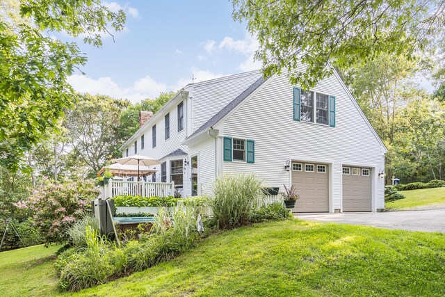 43 Owl Pond Rd, Brewster, MA 02631 - rear view of property featuring an attached garage, asphalt driveway, a chimney, and a yard