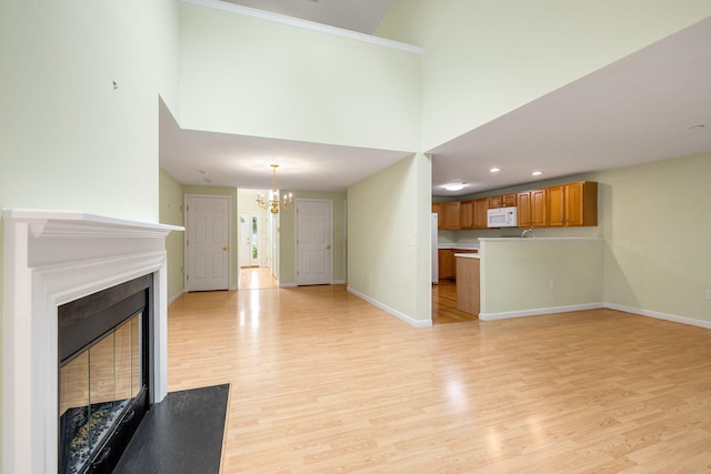 15 Pebble Beach Ave, Mashpee, MA 02649 - unfurnished living room featuring a chandelier, light wood finished floors, a glass covered fireplace, and a towering ceiling