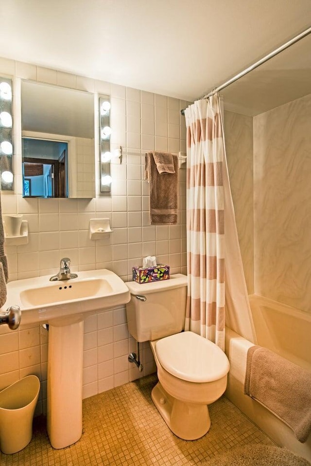 bathroom with shower / bath combination with curtain, tile patterned floors, toilet, and tile walls