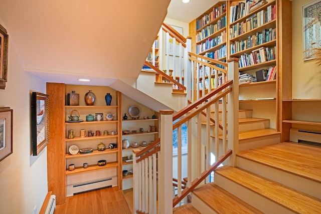 stairway with a baseboard radiator and hardwood / wood-style floors