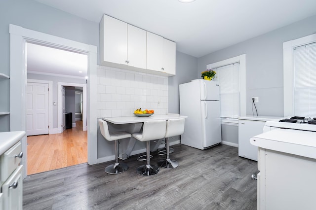 352 Bishop St, Framingham, MA 01702 - kitchen with freestanding refrigerator, light countertops, white cabinetry, light wood-type flooring, and crown molding