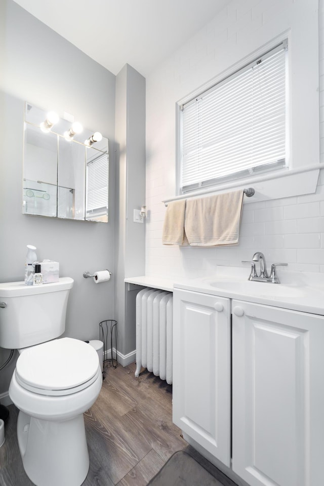 352 Bishop St, Framingham, MA 01702 - bathroom featuring radiator heating unit, wood finished floors, toilet, vanity, and backsplash