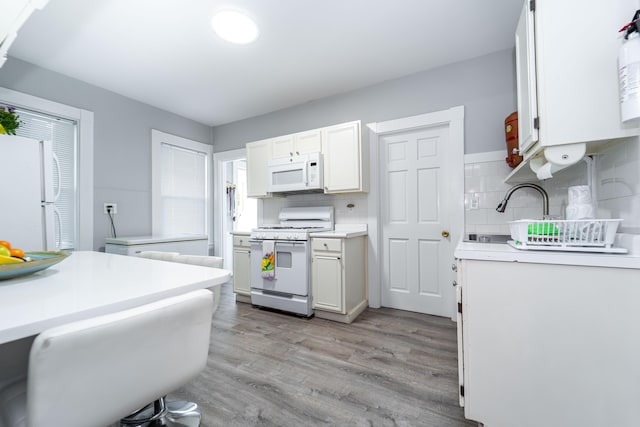 352 Bishop St, Framingham, MA 01702 - kitchen with white appliances, light wood-style flooring, light countertops, decorative backsplash, and white cabinets