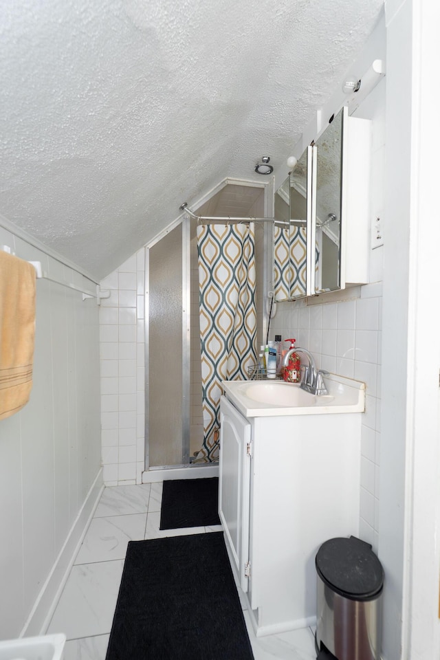 352 Bishop St, Framingham, MA 01702 - bathroom with a textured ceiling, a shower stall, vaulted ceiling, vanity, and marble look tiles