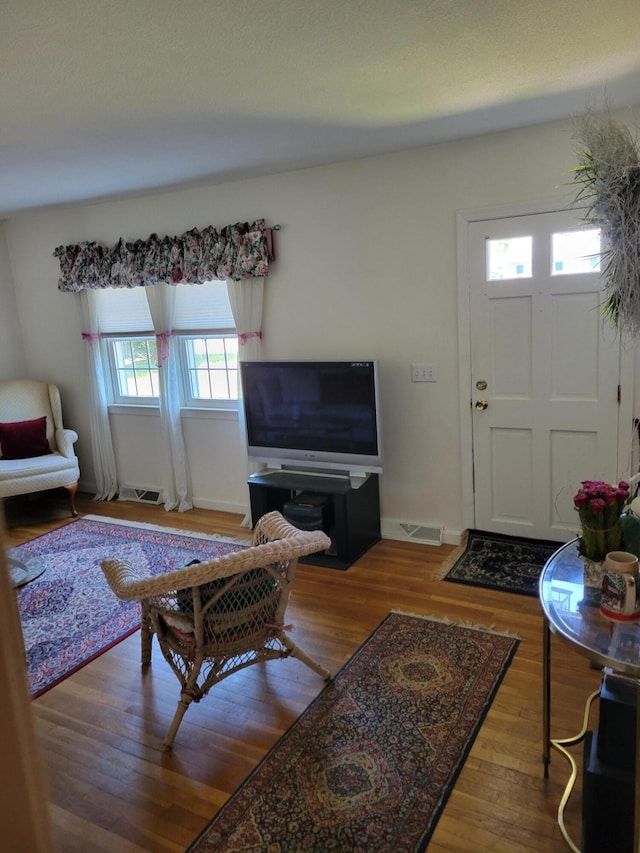 living area featuring visible vents, baseboards, and wood finished floors