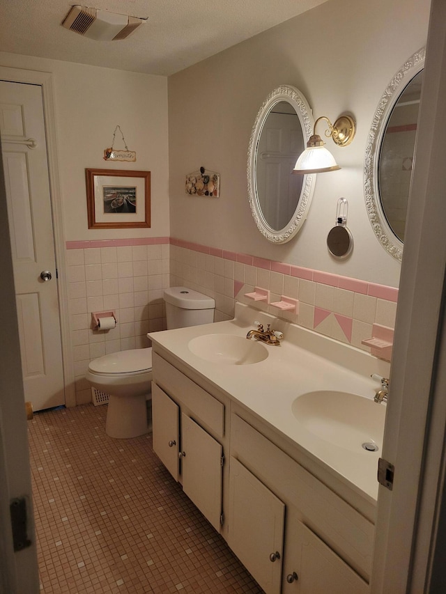 115 Captain Chase Rd, South Yarmouth, MA 02664 - full bathroom featuring wainscoting, tile walls, toilet, double vanity, and tile patterned flooring