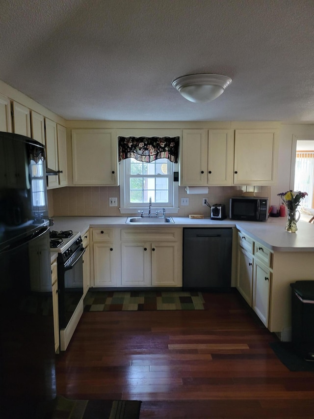 kitchen with black microwave, dishwashing machine, gas stove, fridge, and a sink