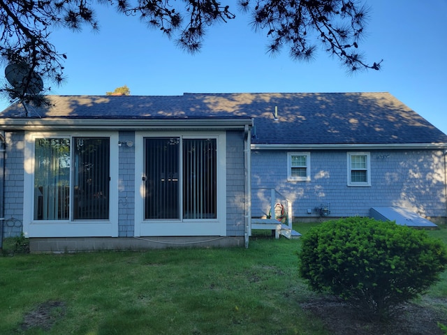 back of house featuring a yard and roof with shingles