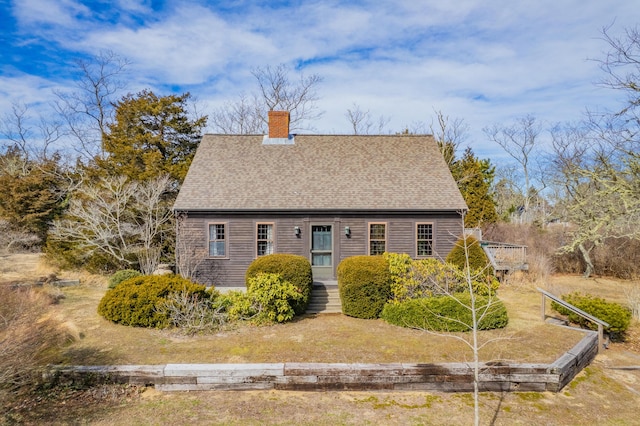 new england style home with a chimney and roof with shingles