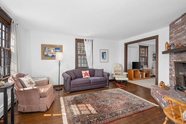 living area featuring a brick fireplace and wood finished floors