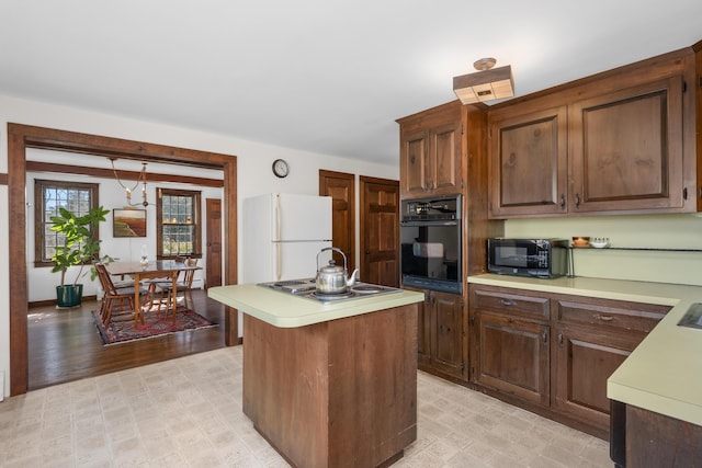 kitchen featuring a kitchen island, light floors, black appliances, and light countertops