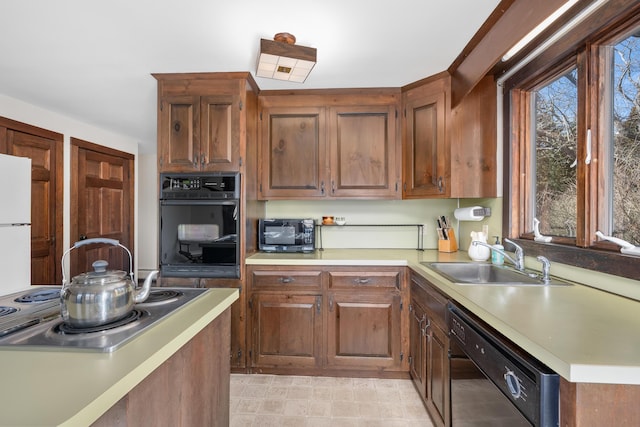 kitchen with black appliances, brown cabinetry, light countertops, and a sink