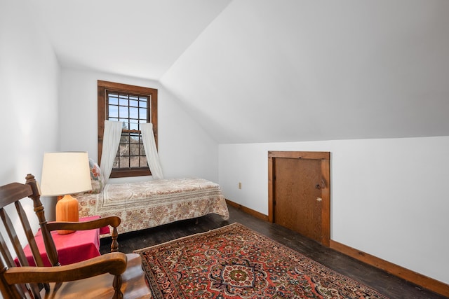 bedroom featuring baseboards, lofted ceiling, and wood finished floors