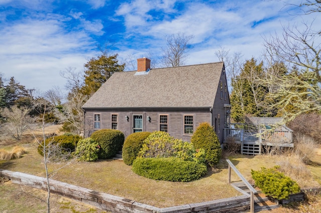 exterior space with a deck, a chimney, and a shingled roof