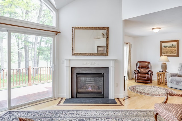 13 Laurel Hill Ct, Bourne, MA 02532 - living area featuring wood finished floors, a fireplace with flush hearth, high vaulted ceiling, and baseboards
