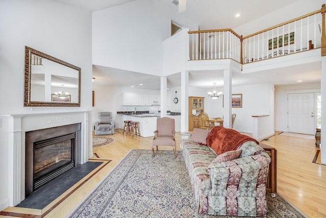 13 Laurel Hill Ct, Bourne, MA 02532 - living room with a chandelier, light wood-type flooring, a towering ceiling, a fireplace, and recessed lighting