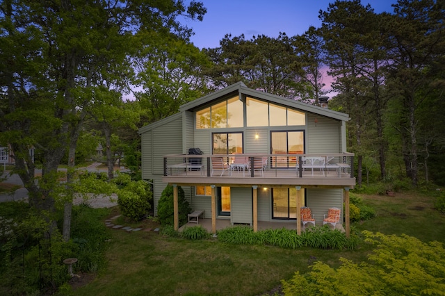 128 Whippoorwill Cir, Mashpee, MA 02649 - back of property at dusk with a patio, a deck, and a lawn