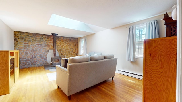 10 Freeman Rd, Yarmouth Port, MA 02675 - living area featuring a baseboard heating unit, a wood stove, light wood-style flooring, and a skylight