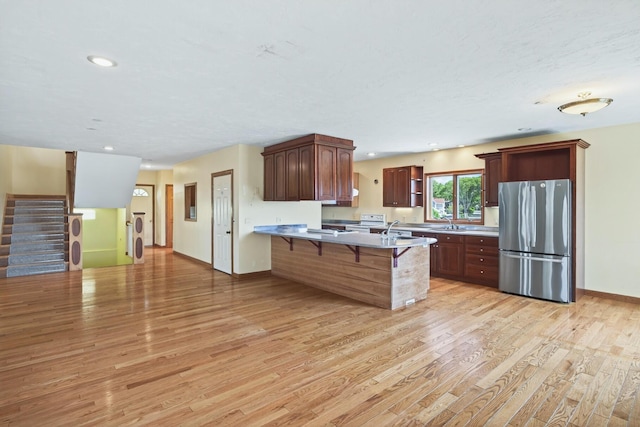 12 Groveland St, Buzzards Bay, MA 02532 - kitchen featuring freestanding refrigerator, a peninsula, a kitchen breakfast bar, light wood-type flooring, and light countertops