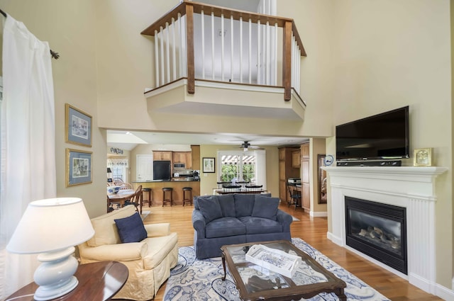 4 Square Rigger Ln, Hyannis, MA 02601 - living room with light wood-style floors, a high ceiling, a glass covered fireplace, and a ceiling fan