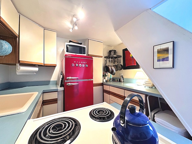 kitchen featuring sink, range with electric cooktop, and fridge