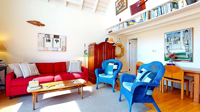 living room with a towering ceiling, baseboard heating, and wood-type flooring