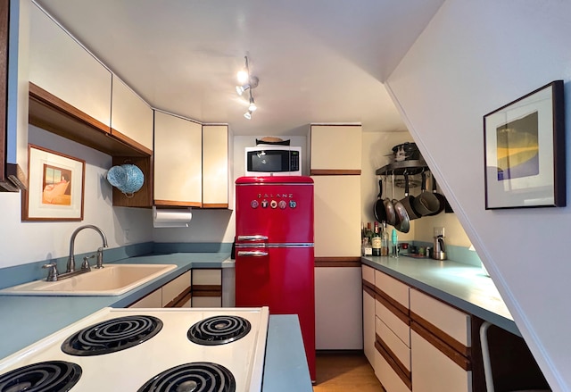 kitchen featuring sink, rail lighting, and white appliances