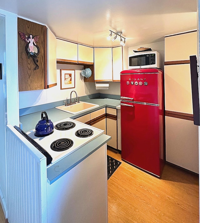 kitchen with sink, white appliances, white cabinetry, and light wood-type flooring